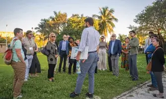 Members of the Commission on Accelerating Climate Action stand in a grassy park in Miami’s Little River neighborhood while on a walking tour led by staff at the Miami-Dade County Office of Resilience.