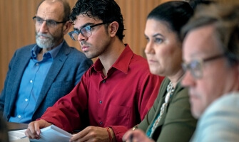 Four members of the Commission on Accelerating Climate Action sit in a row and watch a presentation during the commission’s meeting in Miami. 