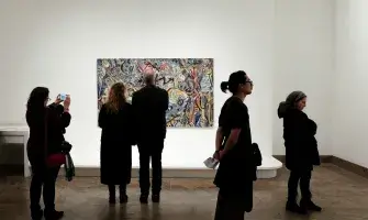 A gallery with people and a painting. 