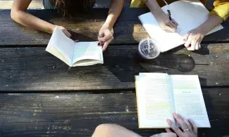 View from above of people at a table reading and writing.