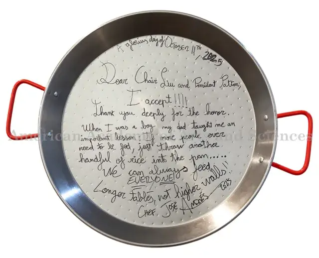 Image of silver paella pan with red handles, with letter from Jose Andres written in black ink on the pan.