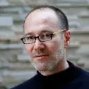 A photo of Paul Dagum, a person with light skin and short dark hair, wearing glasses and a black turtleneck, and facing the viewer.