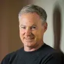 A photo of Eric Horvitz, a person with light skin and short gray hair, wearing a dark shirt, and smiling at the viewer.