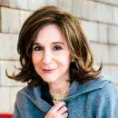 A photo of Sherry Turkle, a person with light skin and long brown hair, wearing a blue suit, and smiling at the viewer.