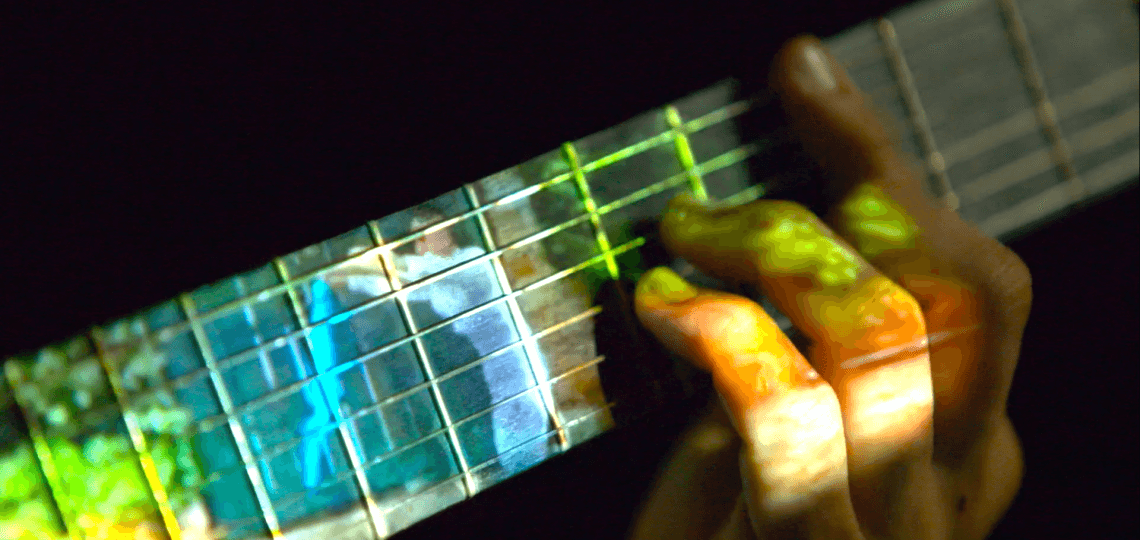The neck of a guitar with image projected on it. 