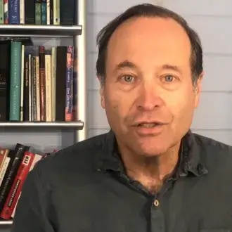 Jeffrey Brown Seen with a Bookshelf Behind Him 