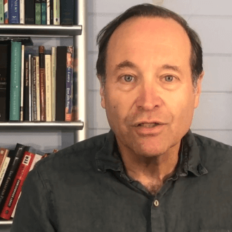 Jeffrey Brown Seen with a Bookshelf Behind Him 