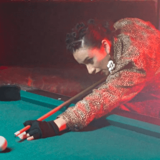 A woman playing pool aims at the cue ball. 