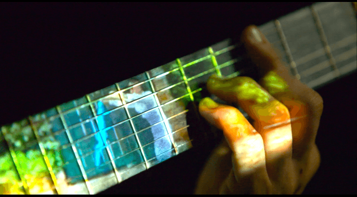The neck of a guitar with image projected on it. 