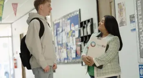 Hallway conversation in a school with a student and advisor from rootEd Alliance. 