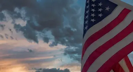 American fly against a sky that has both storm clouds and sun. 