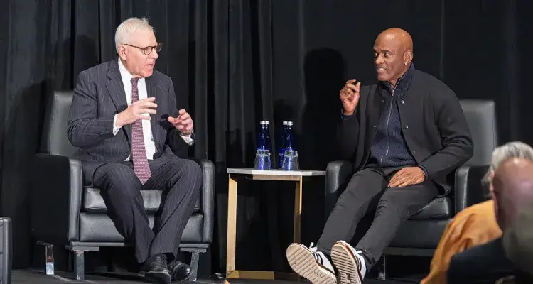 Two formally dressed adults in conversation on a stage.