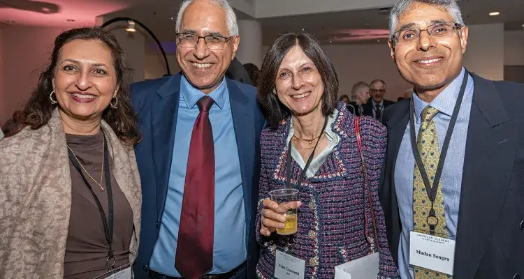 Four formally dressed adults pose and smile at a reception.