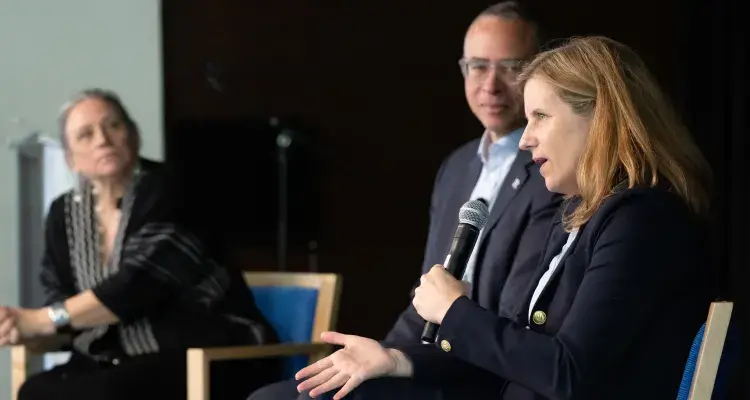 Three adults on stage during a panel