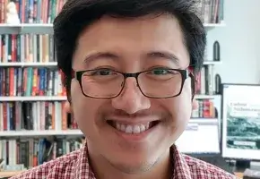 Victor Seow with bookshelves in background. 