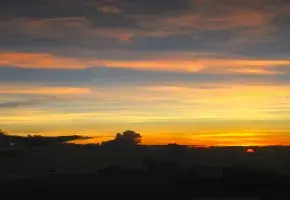 The Sun Descends into the Landscape with Orange Yellow and Bluegray Sky