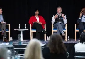 Four adults on stage during a panel