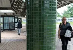 At a public transportation hub, a woman approaches and a man walks away.
