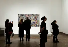A gallery with people and a painting. 