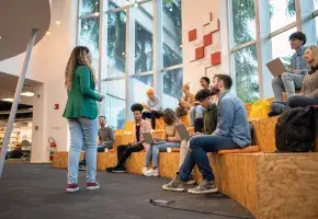 Woman engaging college students in an amphitheater seating arrangement.