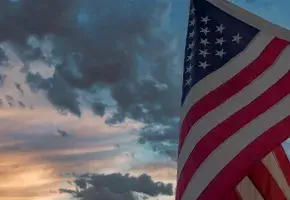 American fly against a sky that has both storm clouds and sun. 