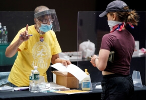 A poll worker and voter wear masks to prevent the spread of COVID-19 during a U.S. primary election.