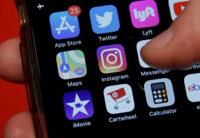 A person holds a phone showing the Instagram app icon. | Jeff Chiu/AP