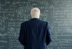 Older man in blazer facing chalkboard filled with equations.