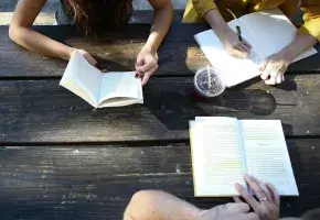 View from above of people at a table reading and writing.