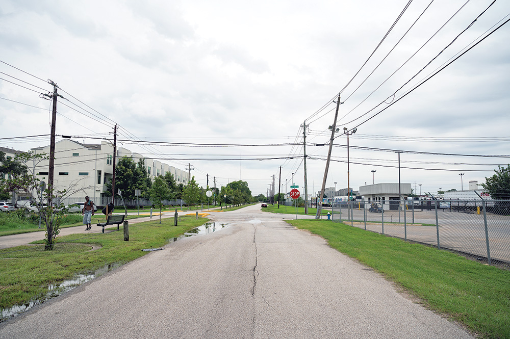 An empty urban street. A man, shirtless, walks along one sidewalk. One of the telephone poles is leaning precariously. 