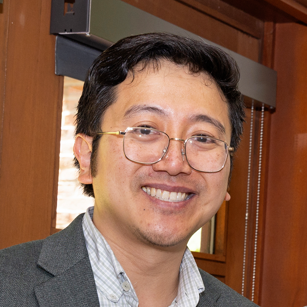 A photo of Victor Seow, an individual with short black hair, wearing glasses and a business shirt and jacket. He is smiling at the viewer.